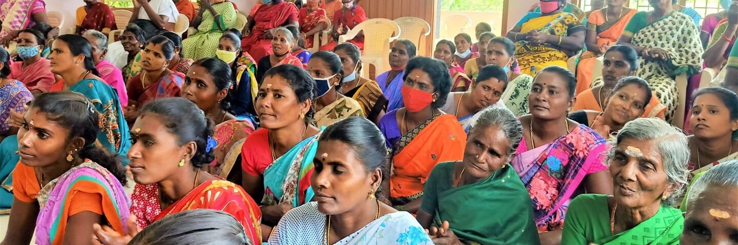 a group of women in saris sat listening and clapping